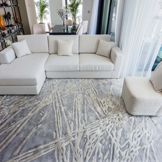 Handmade silver-grey rug with raised ivory abstract patterns and a textured finish for contemporary luxury interiors.