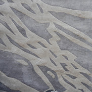 Handmade silver-grey rug with raised ivory abstract patterns and a textured finish for contemporary luxury interiors.