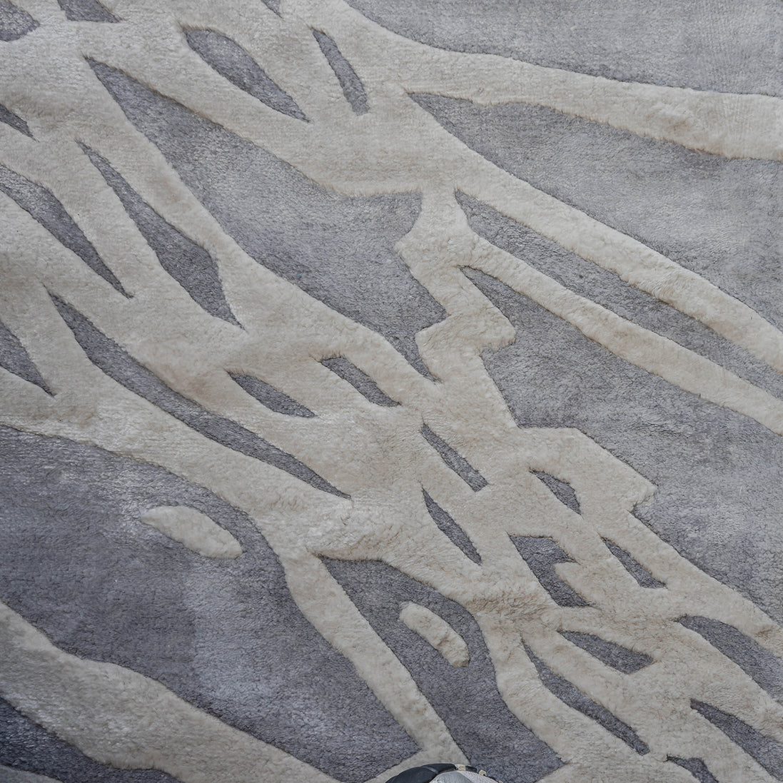 Handmade silver-grey rug with raised ivory abstract patterns and a textured finish for contemporary luxury interiors.