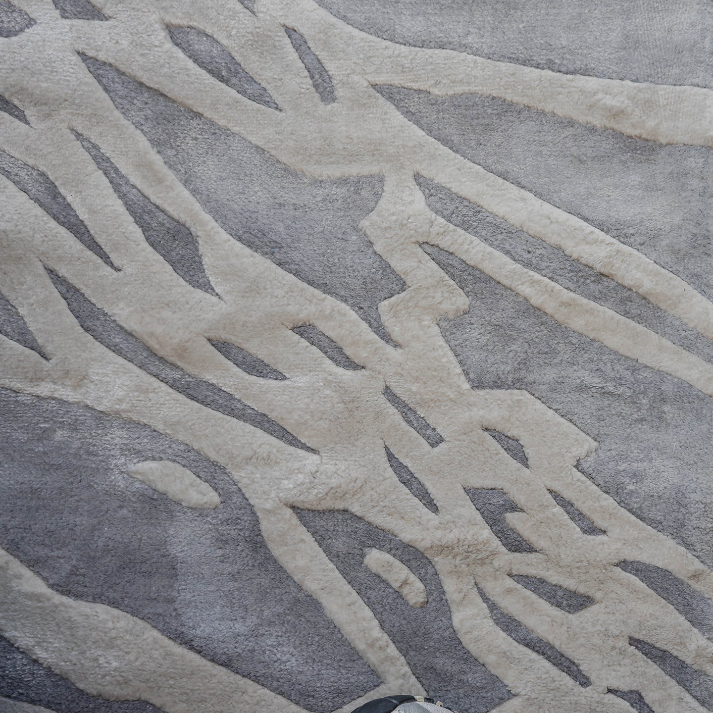 Handmade silver-grey rug with raised ivory abstract patterns and a textured finish for contemporary luxury interiors.