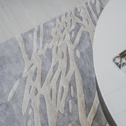 Handmade silver-grey rug with raised ivory abstract patterns and a textured finish for contemporary luxury interiors.