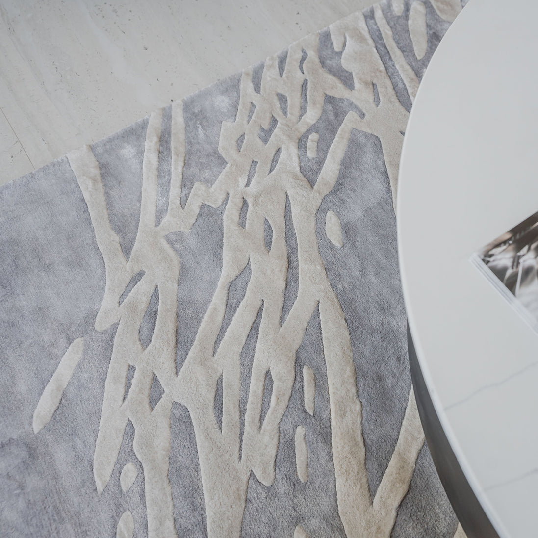Handmade silver-grey rug with raised ivory abstract patterns and a textured finish for contemporary luxury interiors.