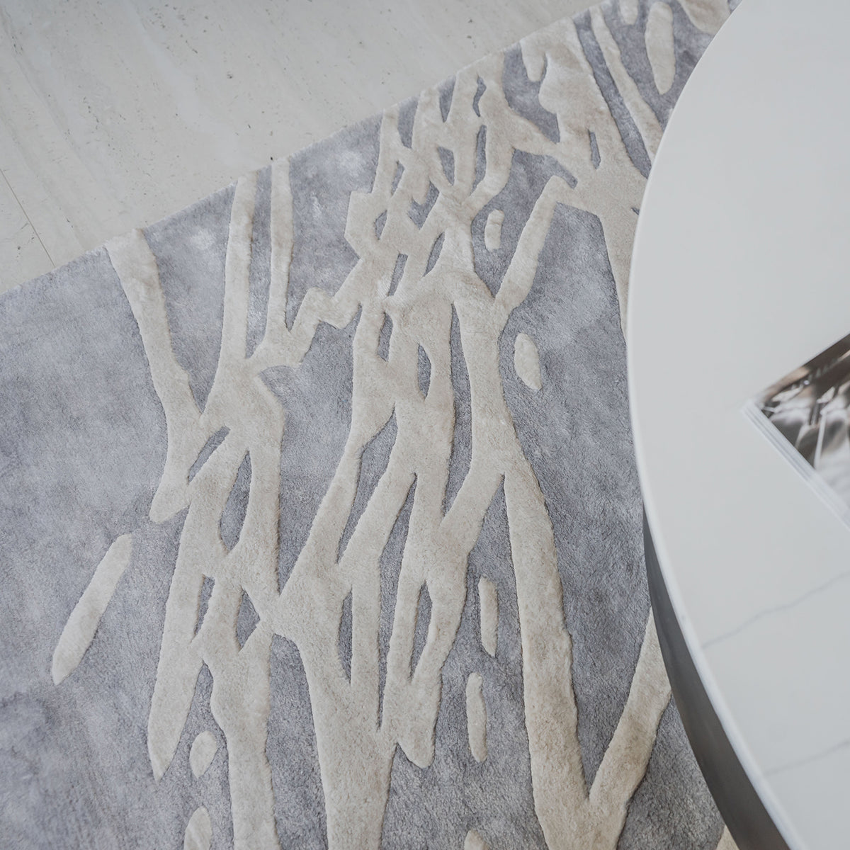 Handmade silver-grey rug with raised ivory abstract patterns and a textured finish for contemporary luxury interiors.