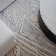 Handmade silver-grey rug with raised ivory abstract patterns and a textured finish for contemporary luxury interiors.