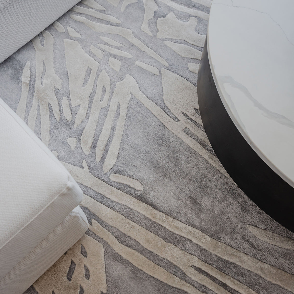 Handmade silver-grey rug with raised ivory abstract patterns and a textured finish for contemporary luxury interiors.