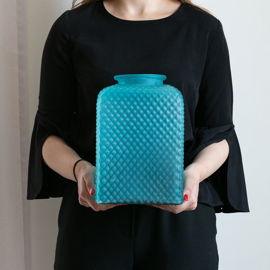 Discover the Speckle Textured Glass Vase in light blue or amber, featuring a sculptural shape and light-catching speckled finish. Available in two sizes.