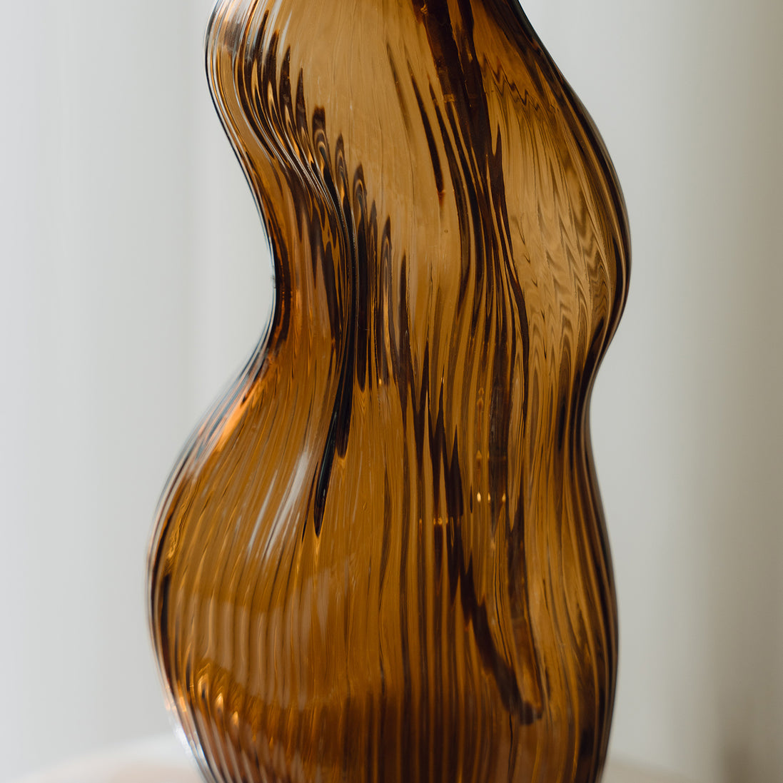 Hand-blown amber glass vase with an organic sculptural silhouette, perfect for modern and luxury interiors.