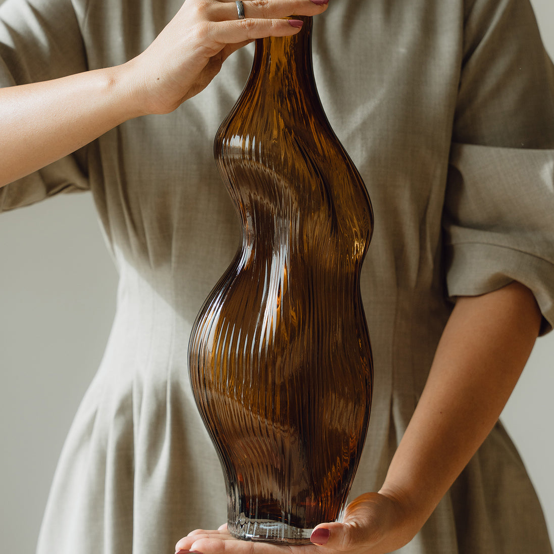 Hand-blown amber glass vase with an organic sculptural silhouette, perfect for modern and luxury interiors.