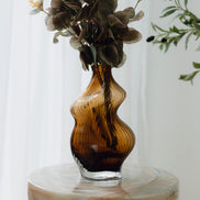 Hand-blown amber glass vase with an organic sculptural silhouette, perfect for modern and luxury interiors.