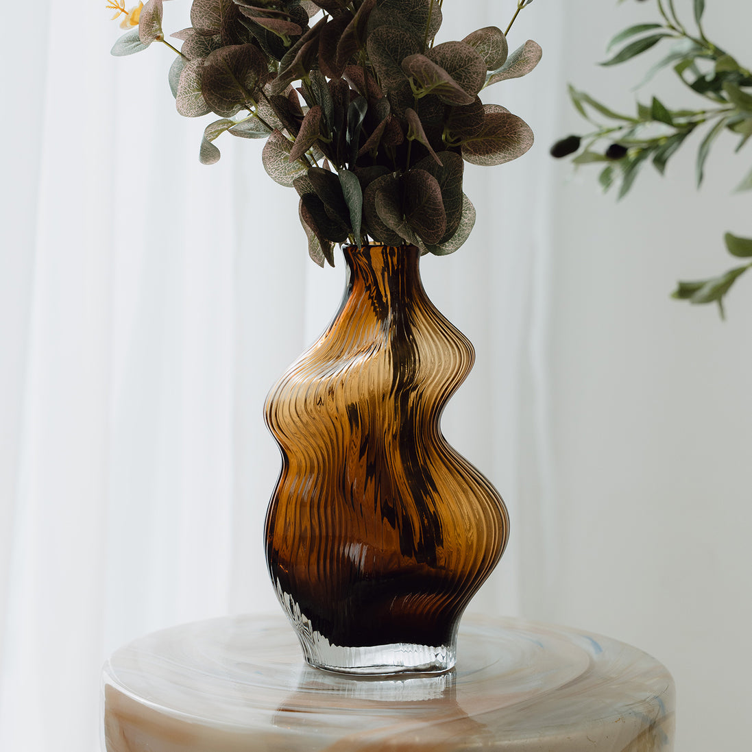 Hand-blown amber glass vase with an organic sculptural silhouette, perfect for modern and luxury interiors.
