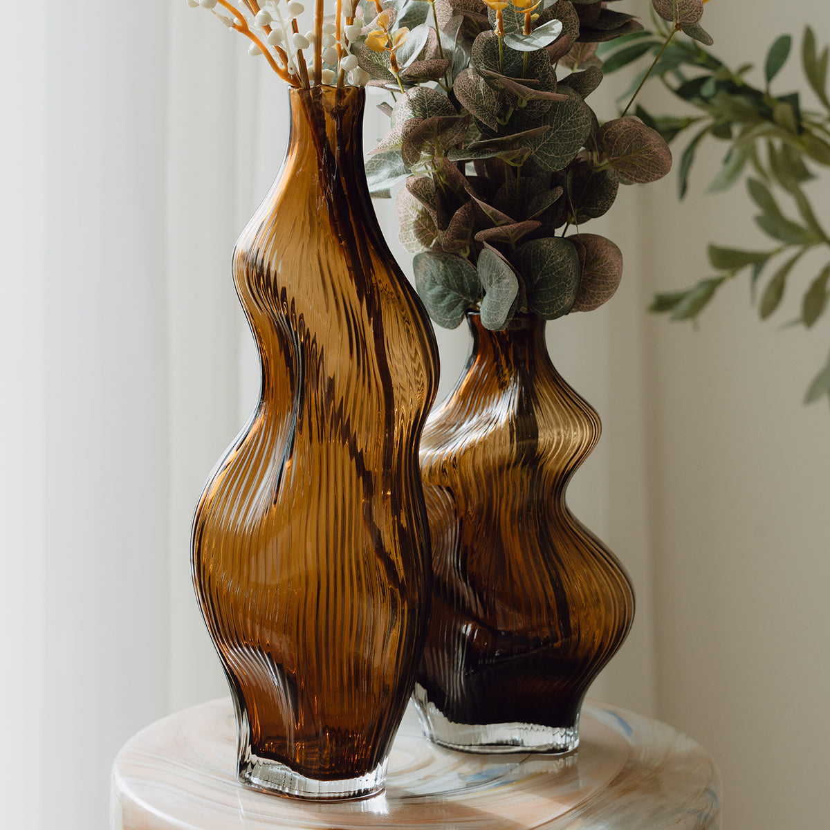 Hand-blown amber glass vase with an organic sculptural silhouette, perfect for modern and luxury interiors.