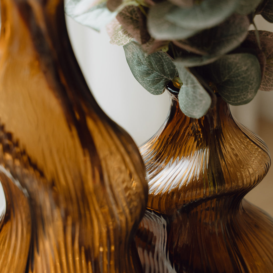 Hand-blown amber glass vase with an organic sculptural silhouette, perfect for modern and luxury interiors.